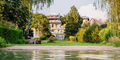 Hotels am See - Liegewiese direkt am See - Kärnten - Ansicht vom Hotel vom Uferbereich aus - Erwachsenenhotel "das Moser - Hotel am See"