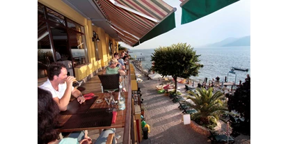Hotels am See - Klassifizierung: 3 Sterne - Italien - Das Taki Restaurant, die ganze Saison über geöffnet, entwickelt ständig seinem Menü mit immer frische Produkte unseres Gebiets wie z.B.: Spargel im Frühling und Spezial Rezepte mit Trüffel des Monte Baldo Gebirges im Sommer, bis zu den Herbstfrüchten wie unsere Bergpilze mit dem typischen starken Geschmack.
Der wunderbare Seeblick, dass man von der Terrasse des Restaurants Genießen kann, wird Ihr kulinarisches Erlebnis noch hervorragender und magisch verwandeln. Mit den einzigartigen Farben des Gardasees, hell und glänzend unter dem Licht der Mittagssonne oder abends mehr weich und zart beim Sonnenuntergang.Im Menü des Restaurants Taki finden sie eine große Palette an Gerichten und Vorspeisen, alle mit große professionelle Pflege vom Chef zubereitet. Hier finden Sie klassische und regionale Vorspeisen und Hauptgerichten aus Fleisch und Fisch, mit Liebe und Sorgfalt präpariert.
Gourmets haben im Taki Restaurant eine Wahlmöglichkeit zwischen fünf verschiedenen See- und Meeresfischen Arten (in Rotation angeboten), womit ihr kulinarisches Erlebnis in unserem Restaurant starten kann.Wenn Vorspeisen nicht beliebt sind, gibt es kein Problem. Im Taki Restaurant finden Sie eine reiche Auswahl an Hauptgerichten und Nachspeisen, saisonale Rezepte mit Fisch oder Fleisch, fein dekoriert und liebevoll in unserer Küche vorbereitet, damit Sie ihren Geschmack auf einer neuen Ebene genießen können.
Um Ihre Erfahrung in unserem Restaurant bestens zu vervollständigen, bieten wir eine reiche Selektion an hausgemachte Desserts die ihrem Gourmet-Erlebnis im Taki Restaurant unvergesslich machen werden.
Darüber hinaus wird jedes Jahr im Restaurant des Taki Village auch das eigene kalt gepressten Olivenöl und die hausgemachten Marmeladen angeboten, die im reichen kulinarischen Angebot des Restaurants enthalten sind. Unsere Marmeladen sind auch zum Frühstück zu finden. - Taki Village