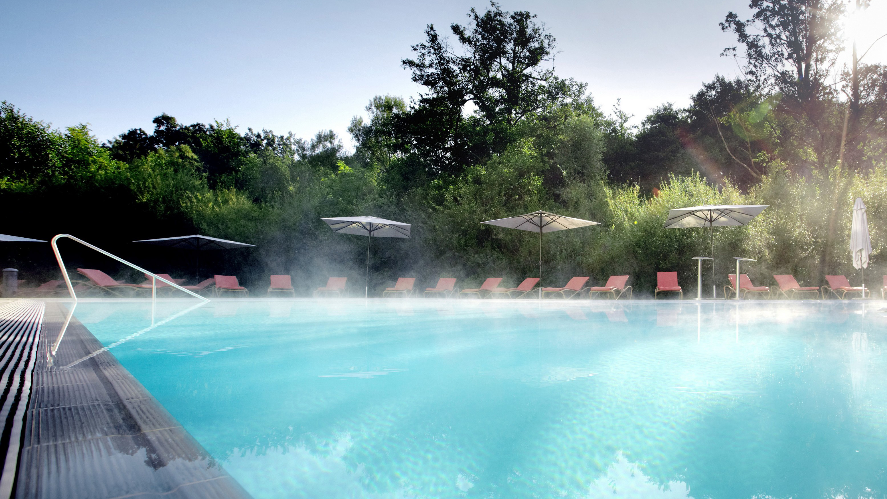 Urlaub am See: Foto vom dampfenden Außenpool, im Hintergrund sieht man Poolliegen und Sonnenschirme - Hotel Esplanade Resort & Spa Bad Saarow