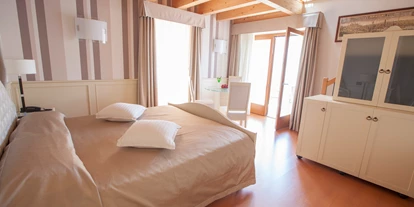 Hotels am See - Verpflegung: Frühstück - Der orientalische und imperiale Stil harmonieren in diesem 55qm Penthouse, welches an an die Sommerresidenz eines englischen Prinzen erinnert.
Große Schlafzimmer, Wohnzimmer im Dach mit Ruheraum nach Art des Sultans und kleine Bibliothek mit Leseecke, 2 Badezimmer (eine von 11 m² mit Whirlpool-Wanne und Dusche und eine von 4/5 m²), 2 schönen Balkonen mit See - und Schwimmbad -Blick (tot. 22 m²). - Belfiore Park Hotel